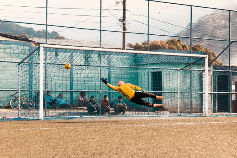 a football player jumping to prevent a goal