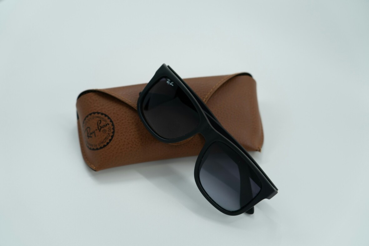 Mustat Ray-Ban Wayfarer lasit ja ruskea nahkakotelo valkoisella taustalla