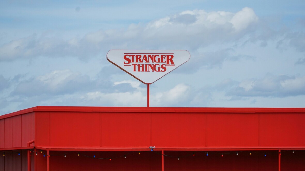 Punavalkoinen Stranger Things -kyltti punaisella katolla pilvistä taivasta vasten
